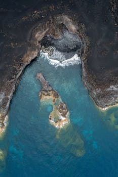 Stunning aerial shot of La Palma's rugged coastline with turquoise waters and dark rocky terrain.
