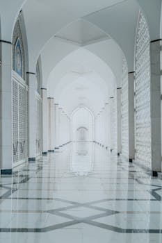 Beautifully designed arched hallway in a mosque featuring Islamic architectural details and marble flooring.