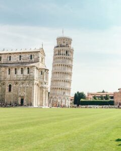 The iconic Leaning Tower of Pisa and adjacent cathedral in a sunny setting.