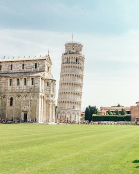 The iconic Leaning Tower of Pisa and adjacent cathedral in a sunny setting.